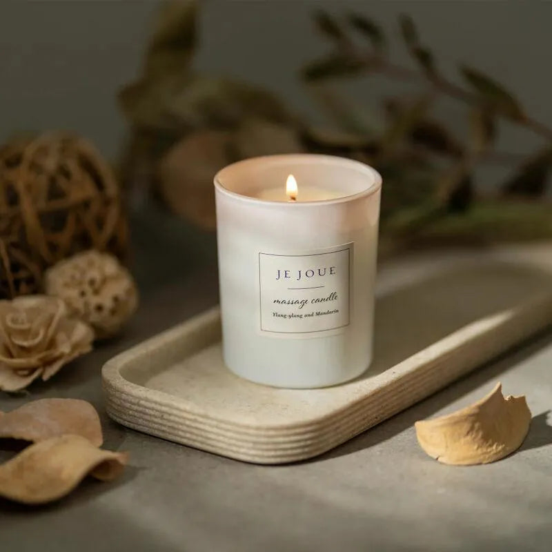 Bougie de massage ylang ylang mandarine allumée, cire de soja, sur plateau bois, ambiance relaxante et intime.