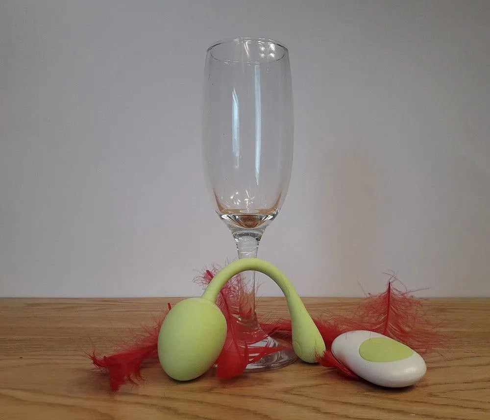Boules de geisha vert pomme avec télécommande, silicone médical, 10 modes vibrations, sur fond de plumes rouges.