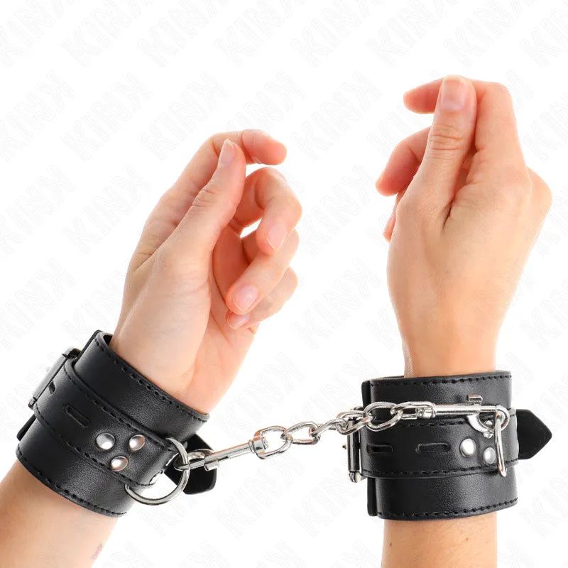 Bracelets BDSM en cuir noir avec rembourrage, boucles métalliques réglables, anneaux D, chaîne de connexion, sur poignets.
