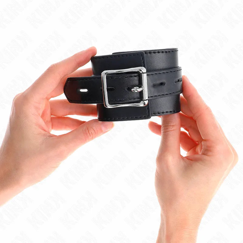 Bracelet BDSM en cuir noir, rembourré, avec boucles métalliques réglables et anneaux D, pour confort et sécurité.