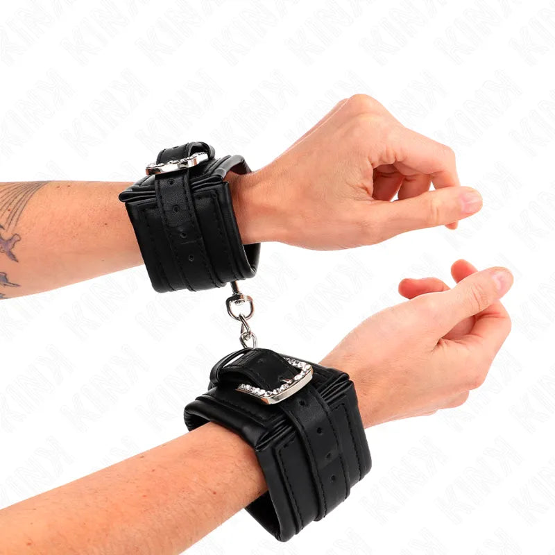 Bracelets BDSM en cuir noir, rembourrés, ajustables avec boucles métalliques robustes pour confort et sécurité.