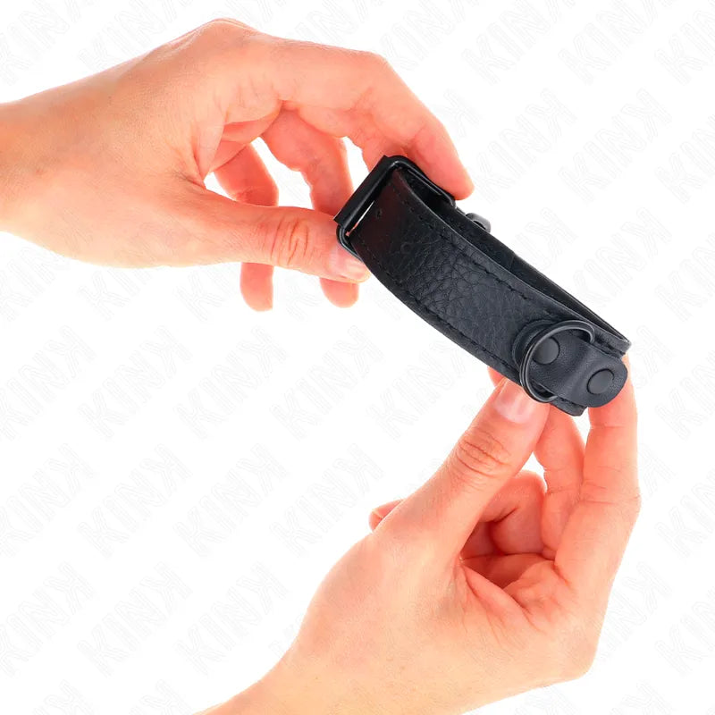 Bracelet BDSM en cuir noir, ajustable, avec boucle velcro robuste, tenu par deux mains, design élégant et sophistiqué.