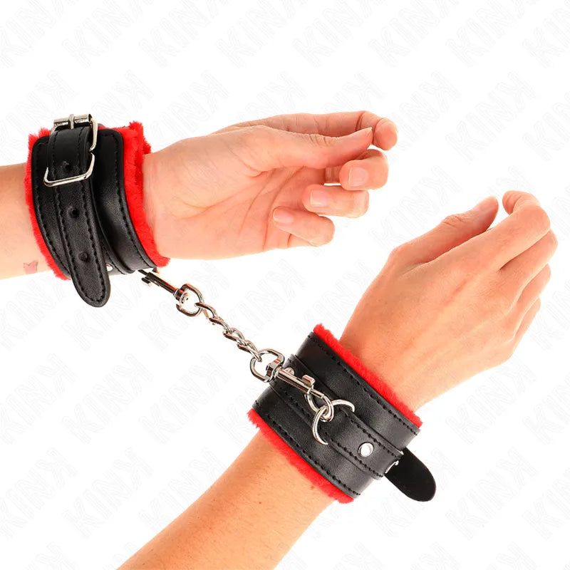 Bracelets BDSM cuir noir rouge rembourrés, ajustables, avec boucles métalliques et chaîne, portés sur poignets.