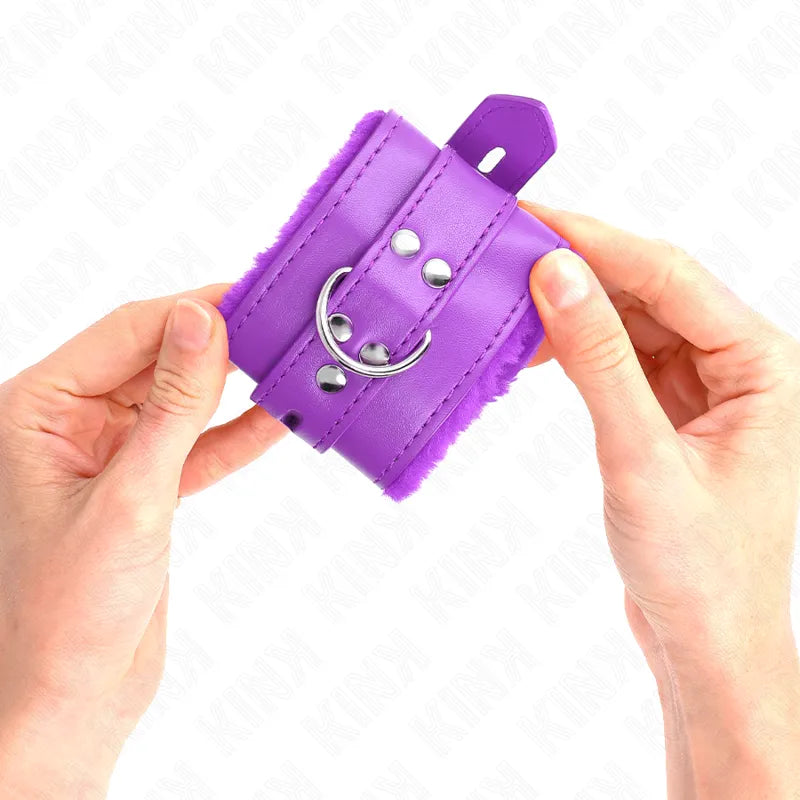 Bracelet BDSM violet en cuir végan rembourré, ajustable avec boucle et anneau, tenu par deux mains.