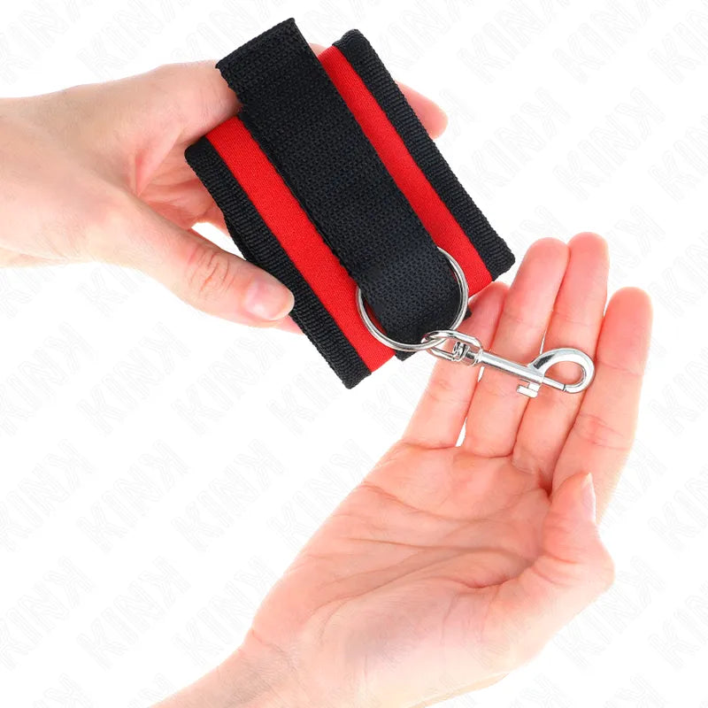 Bracelet BDSM en cuir végétalien noir et rouge, réglable avec anneaux D et boucle métallique, rembourrage intérieur.