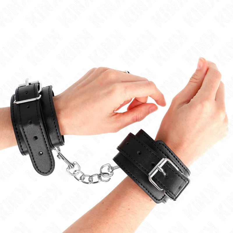Bracelets BDSM cuir noir rembourrés, boucles métalliques robustes, chaîne de maintien, élégance et sécurité.