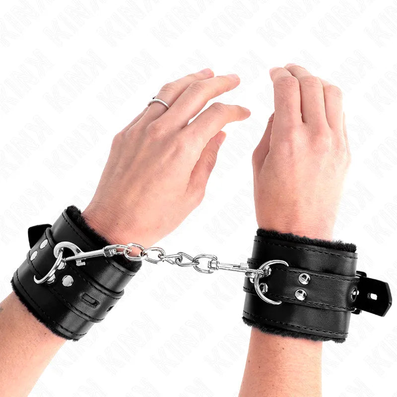 Bracelets BDSM cuir noir rembourrés, boucles métalliques robustes, chaîne centrale, design élégant et confortable.