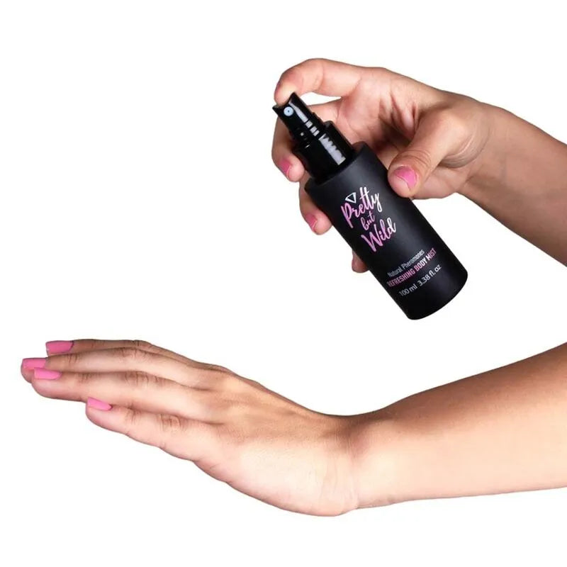 Flacon noir de brume corporelle hydratante anti-cellulite, mains appliquant le produit, fond blanc.