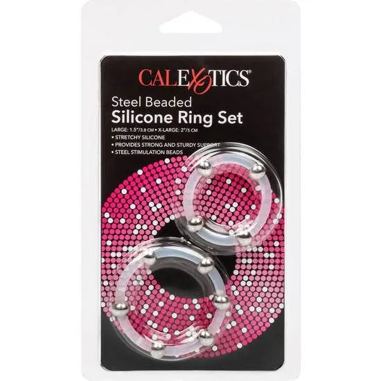 Anneau pénien silicone transparent perlé acier inoxydable, extensible, dans emballage avec fond rose et noir.