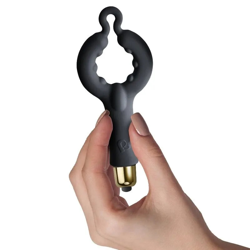 Anneau vibrant noir en silicone doux, forme ergonomique, avec module doré, tenu en main, pour stimulation couple.