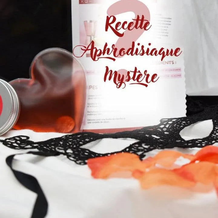 Coffret romantique avec bougie massage, stimulateur rose, pétales tissu, fond noir et rouge, ambiance sensuelle.