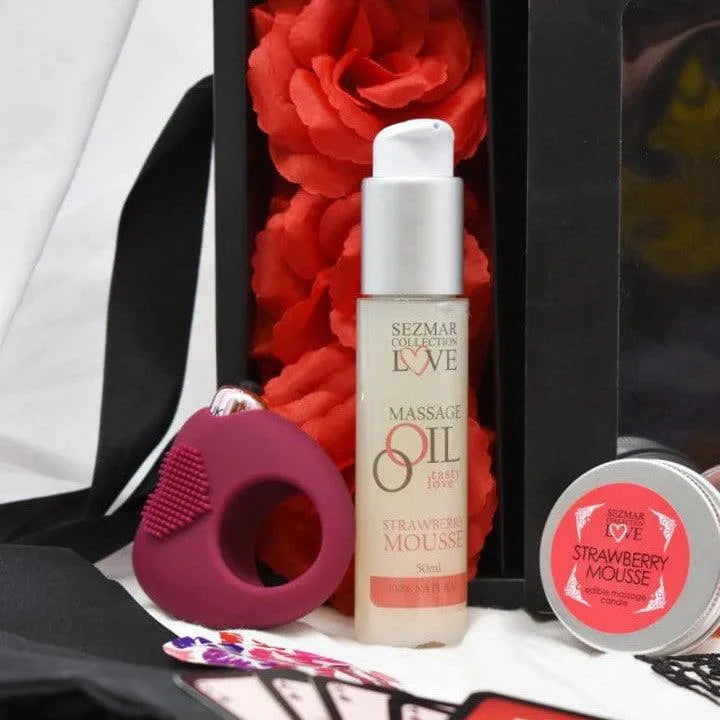 Coffret romantique avec huile de massage, pétales rouges, bandeau satiné, masque dentelle, accessoires intimes.
