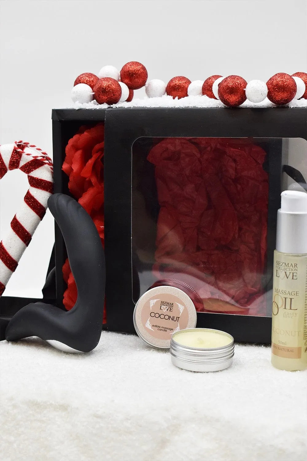 Coffret coquin homme Noël avec huile coco, bougie massage, stimulateur prostate silicone noir, roses rouges, décor festif.