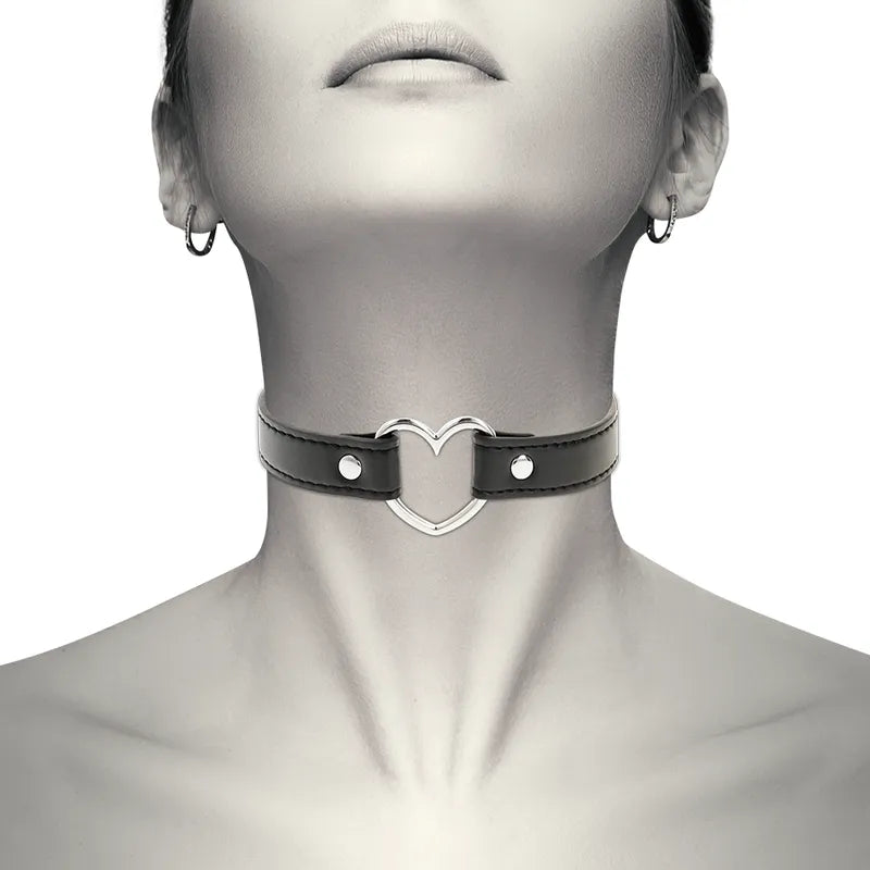 Collier fétiche cuir vegan noir, forme cœur, boutons-pression métal, élégant et ajustable, porté sur un cou féminin.