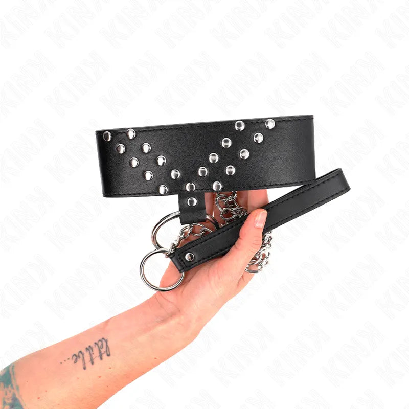 Collier BDSM noir en cuir végétalien avec rivets argentés, design élégant et ajustable, tenu par une main tatouée.