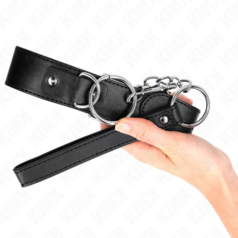 Collier de soumission en cuir noir avec boucles métalliques, élégant et ajustable, tenu dans une main.
