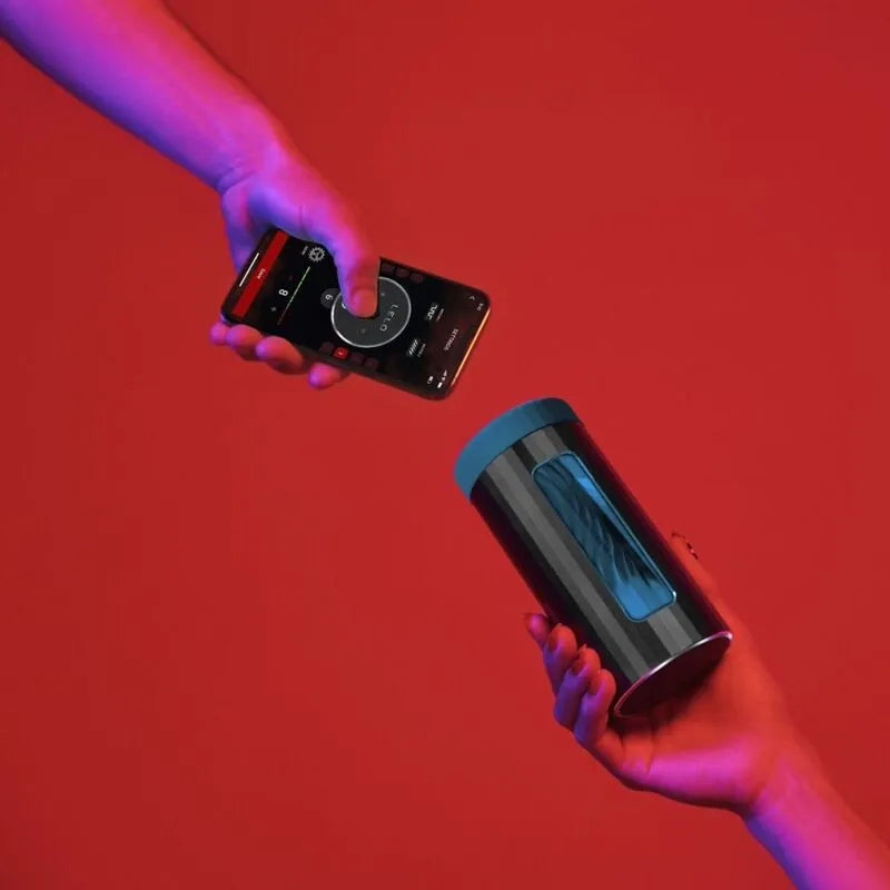 Appareil en silicone noir connecté, forme cylindrique, écran bleu, tenu par une main, contrôlé via smartphone sur fond rouge.