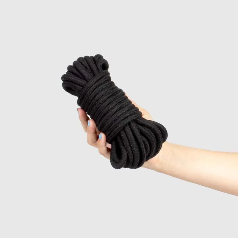 Corde shibari noire 10m coton polyester, douce et sécurisée pour bondage BDSM, tenue dans une main.