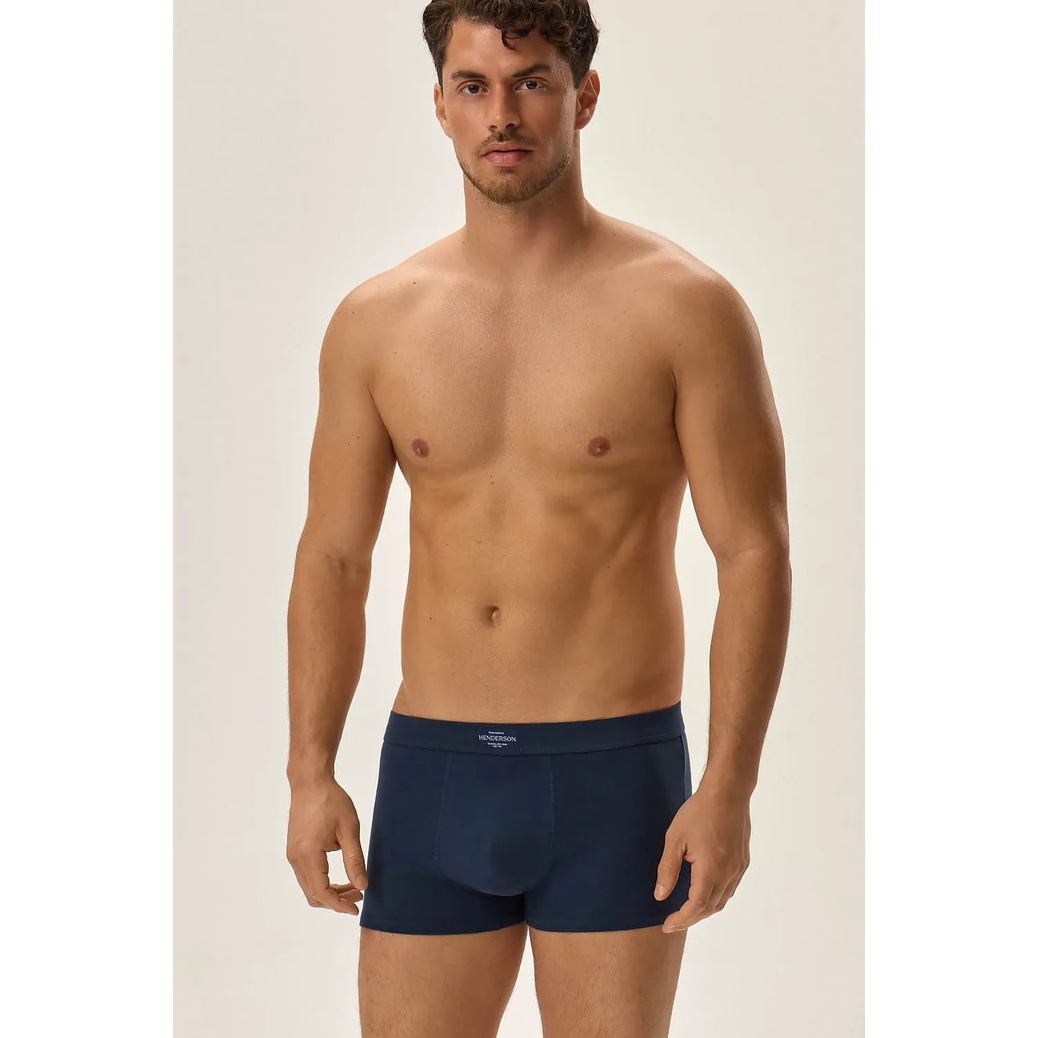 Boxers ajustés Henderson bleu, ceinture élastique renforcée, logo visible, confort coton élasthanne, homme debout.