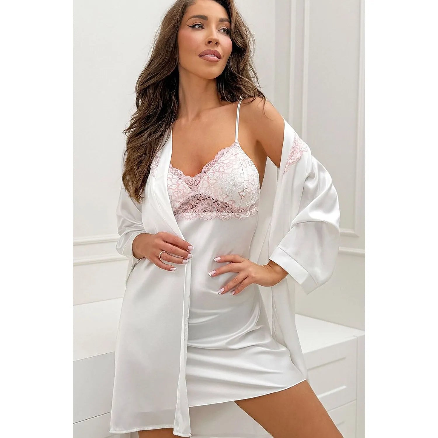 Chemise de nuit satin blanc avec dentelle rose, bretelles fines, élégante et ajustable, portée par une femme dans une cham...