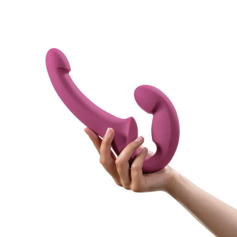 Double gode rose incurvé en silicone médical, sans harnais, ergonomique et flexible, tenu par une main.
