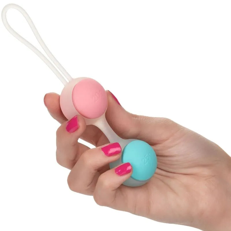 Boules de Geisha en silicone rose et bleu, poids interchangeables, pour tonification pelvienne, tenues dans une main.