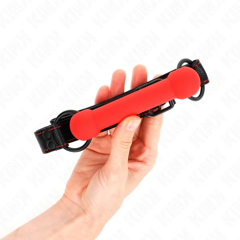 Boule de silicone rouge ergonomique avec sangle noire ajustable pour BDSM, confort et sécurité, vue en main.