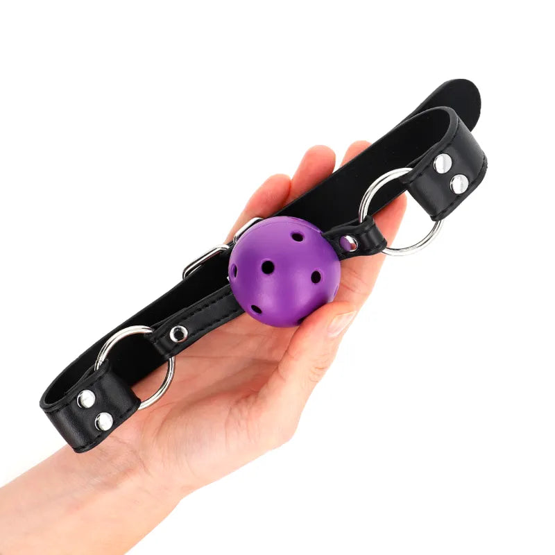 Gag BDSM silicone violet avec sangles noires ajustables, ergonomique et hypoallergénique, pour confort et sécurité.