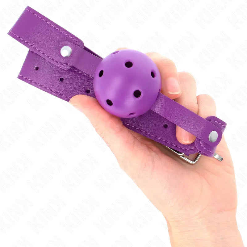 Gag BDSM en silicone violet avec sangle réglable, boule perforée pour confort respirant, tenue en main.