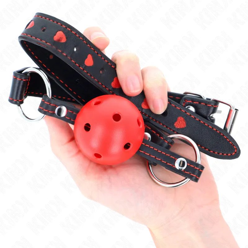 Gag BDSM en silicone rouge avec cerceau noir ajustable, motifs cœurs rouges, boucles métalliques, confort et sécurité.