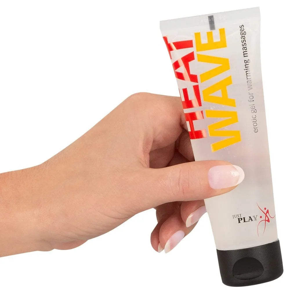 Tube transparent de gel massage chauffant 80ml, bouchon noir, texte rouge et jaune, main tenant le produit.