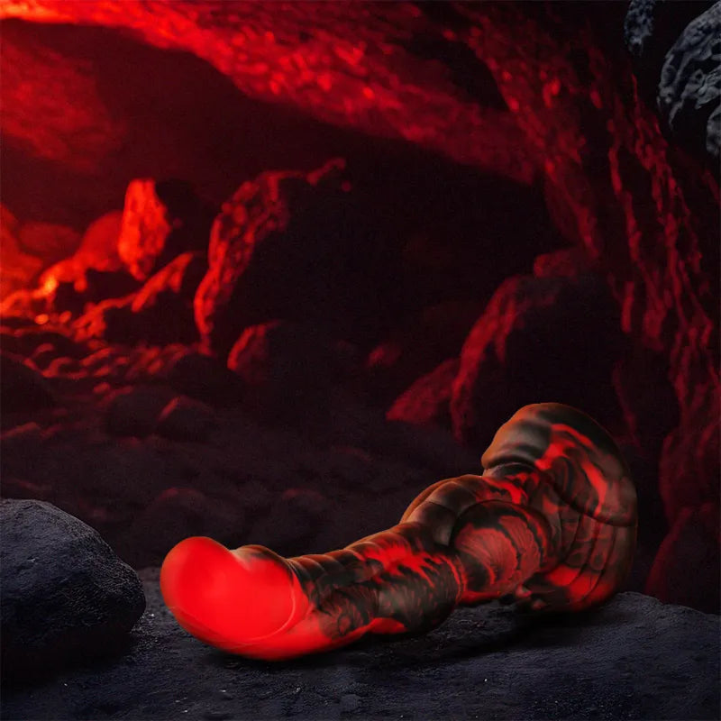 Gode en silicone rouge texturé, inspiré de la mythologie grecque, posé dans une grotte sombre et mystérieuse.