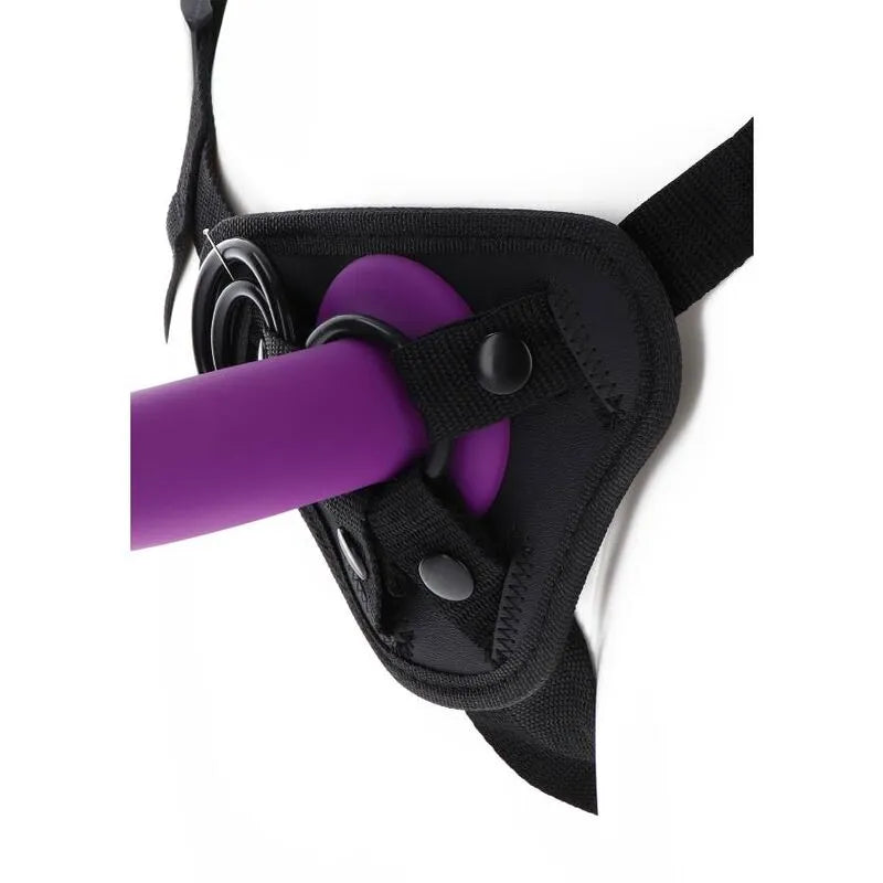 Harnais noir rembourré avec anneaux en silicone, bretelles ajustables, coussin avant et gode violet fixé, vue de près.