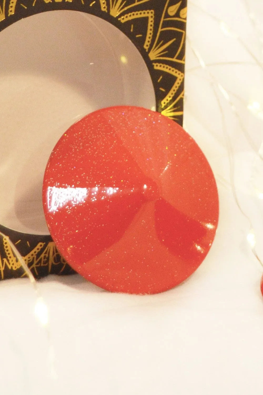 Cône métal rouge brillant réutilisable, design conique élégant, diamètre 51mm, sur fond décoratif lumineux.