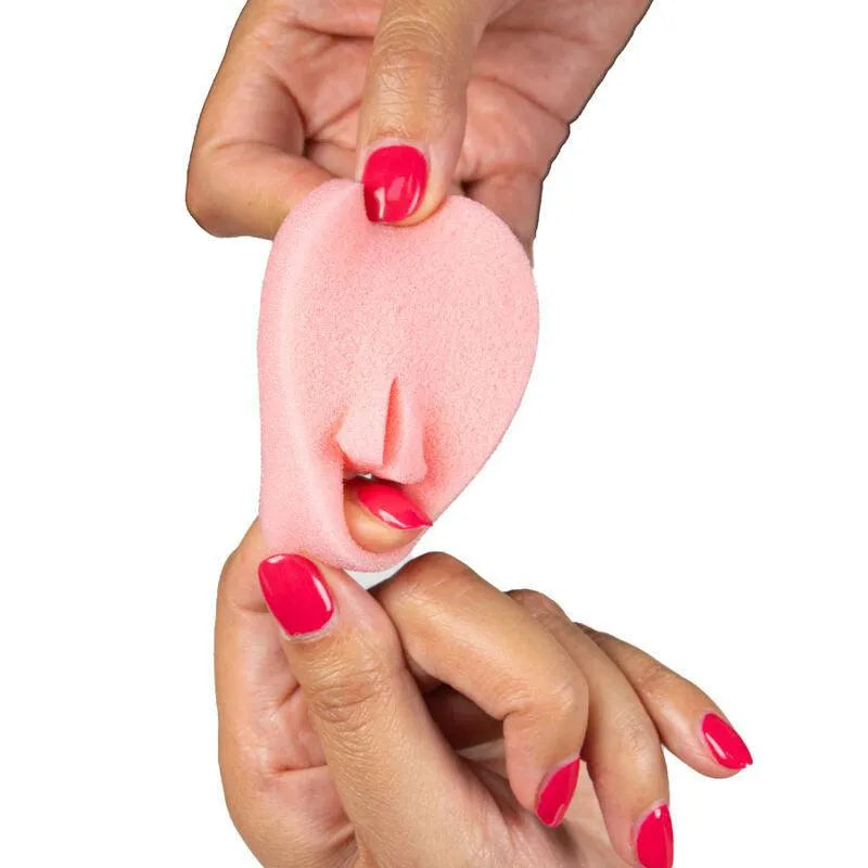 Éponge menstruelle rose flexible en polyuréthane, hypoallergénique, tenue par des mains avec vernis rouge.